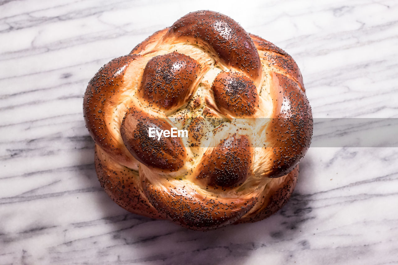 Braided round challah bread loaf with poppy seeds