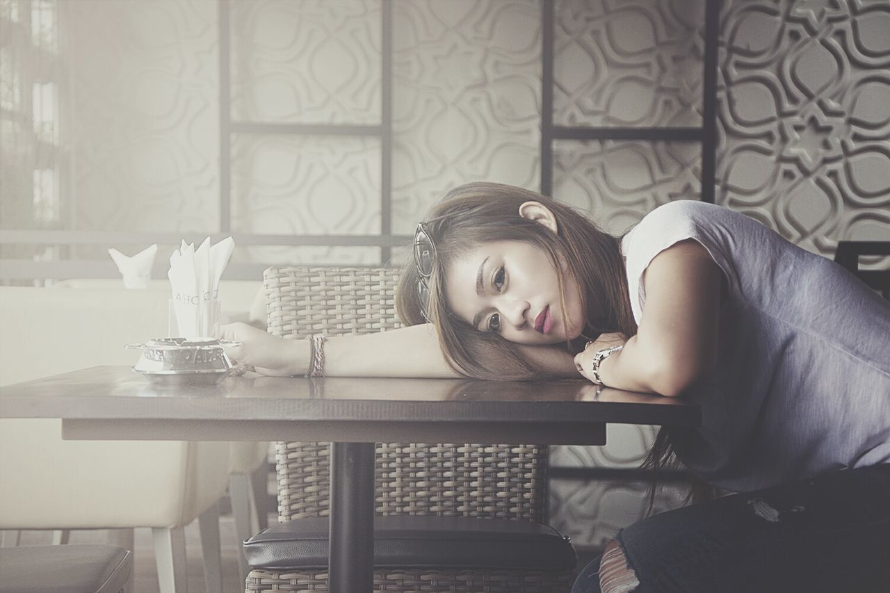 PORTRAIT OF YOUNG WOMAN SITTING ON CHAIR