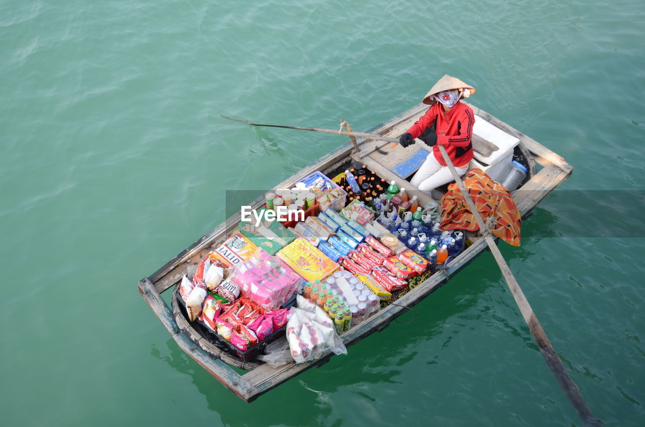 High angle view of woman selling food and drink on boat in river