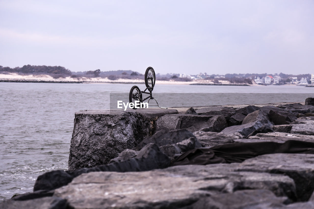 Bicycle on rocks by river against clear sky