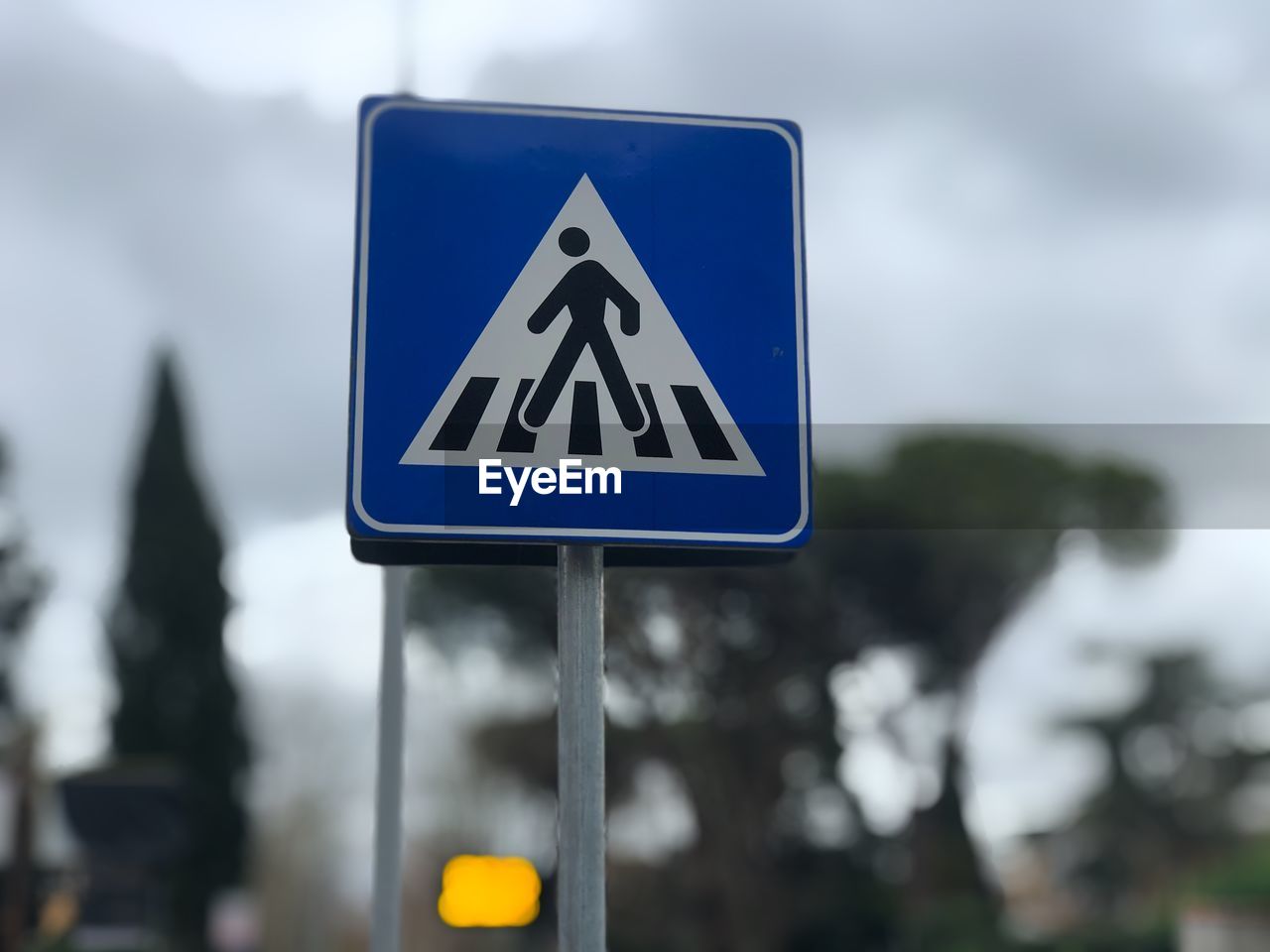 Close-up of road sign of pedestrian crossing against blurred background