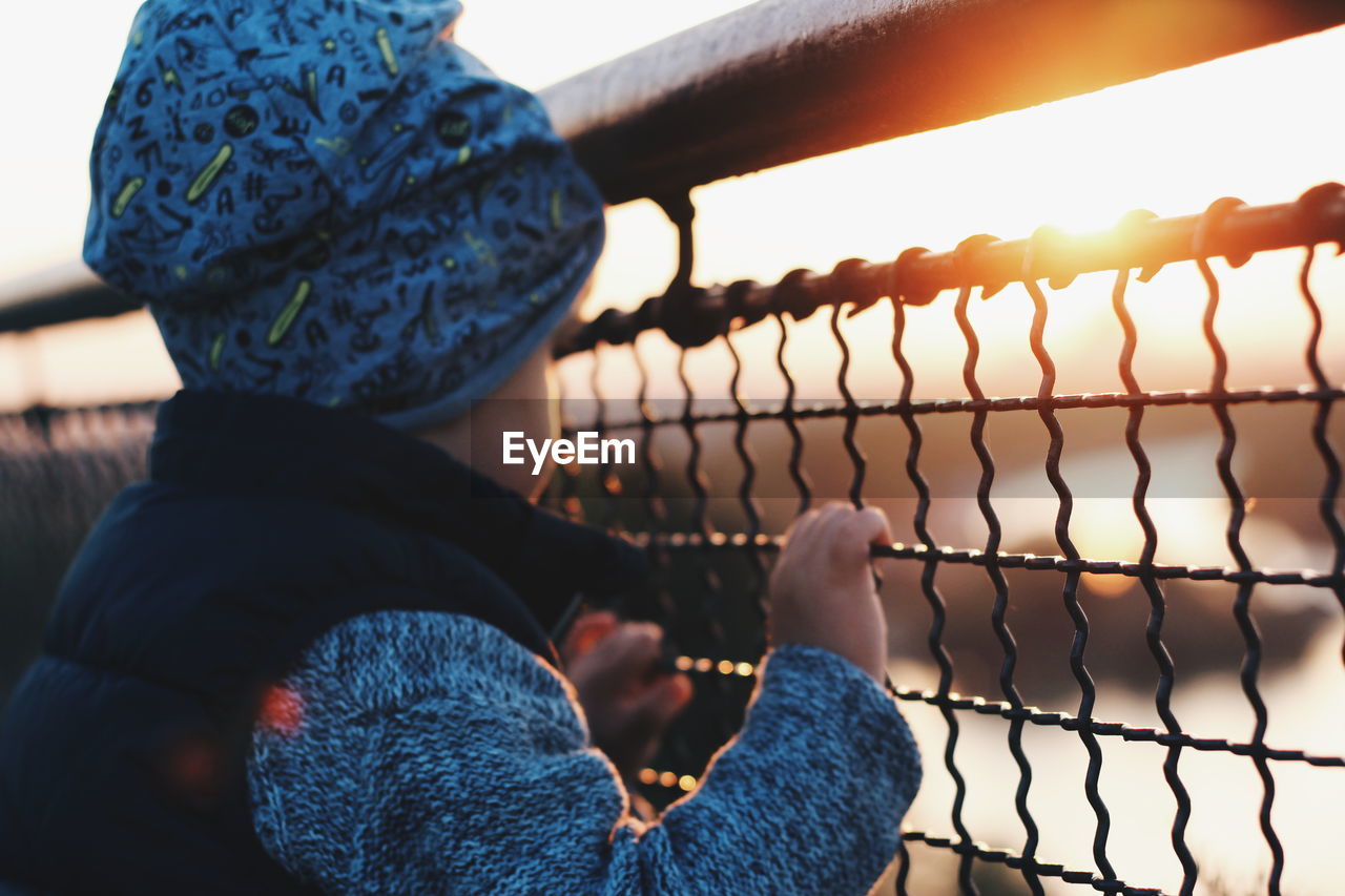 Side view of boy looking through metallic railing