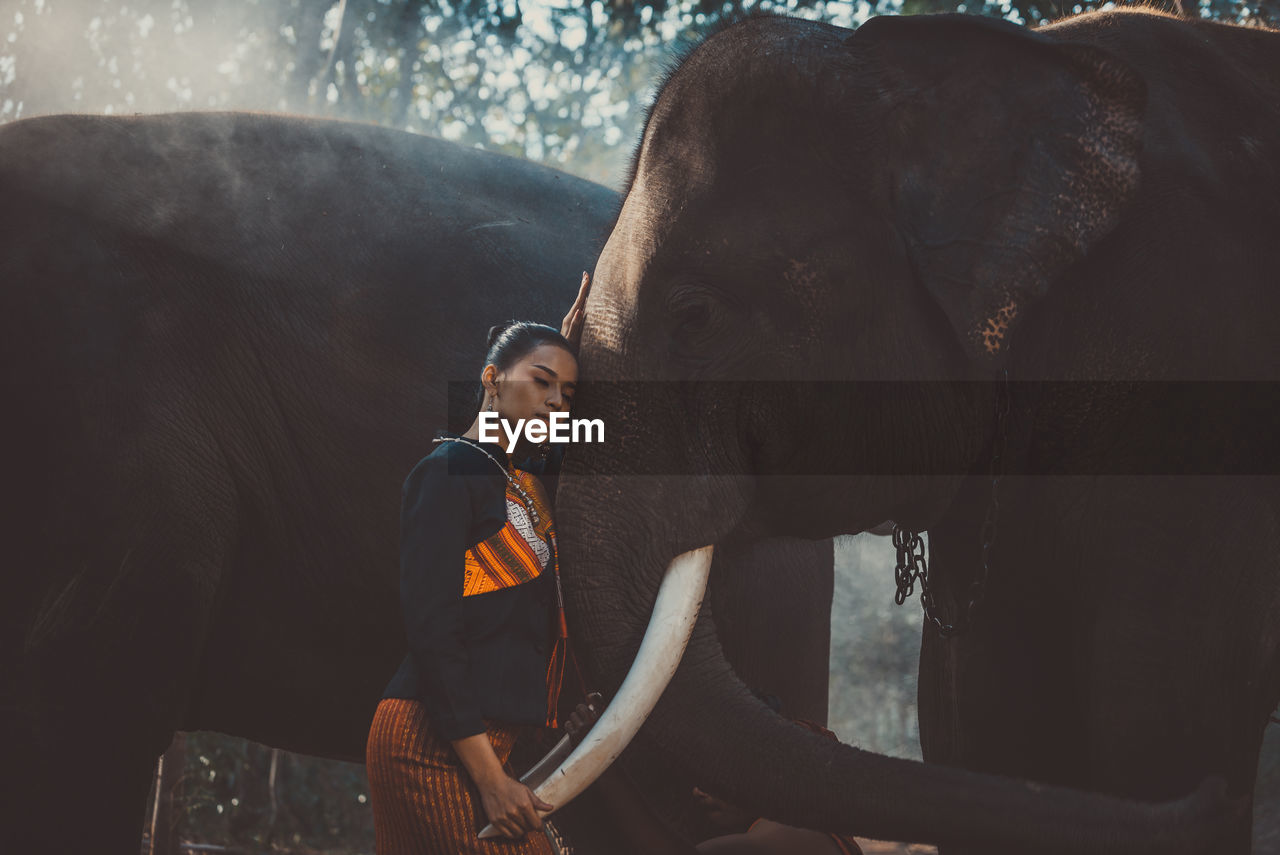 Woman standing with elephant in temple