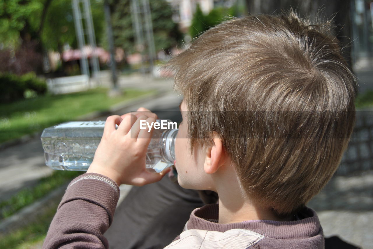 Boy drinking water from bottle in city