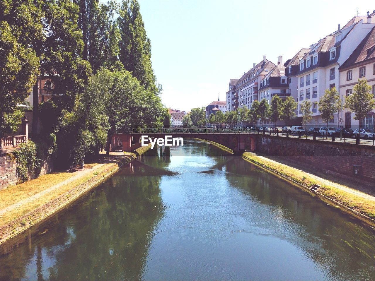 Bridge over river amidst buildings in city against sky