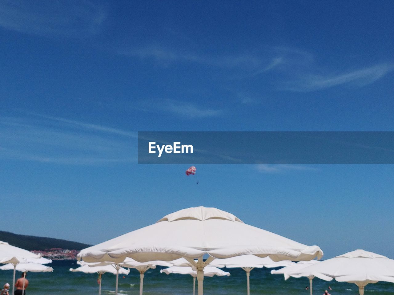 White umbrella on beach against blue sky