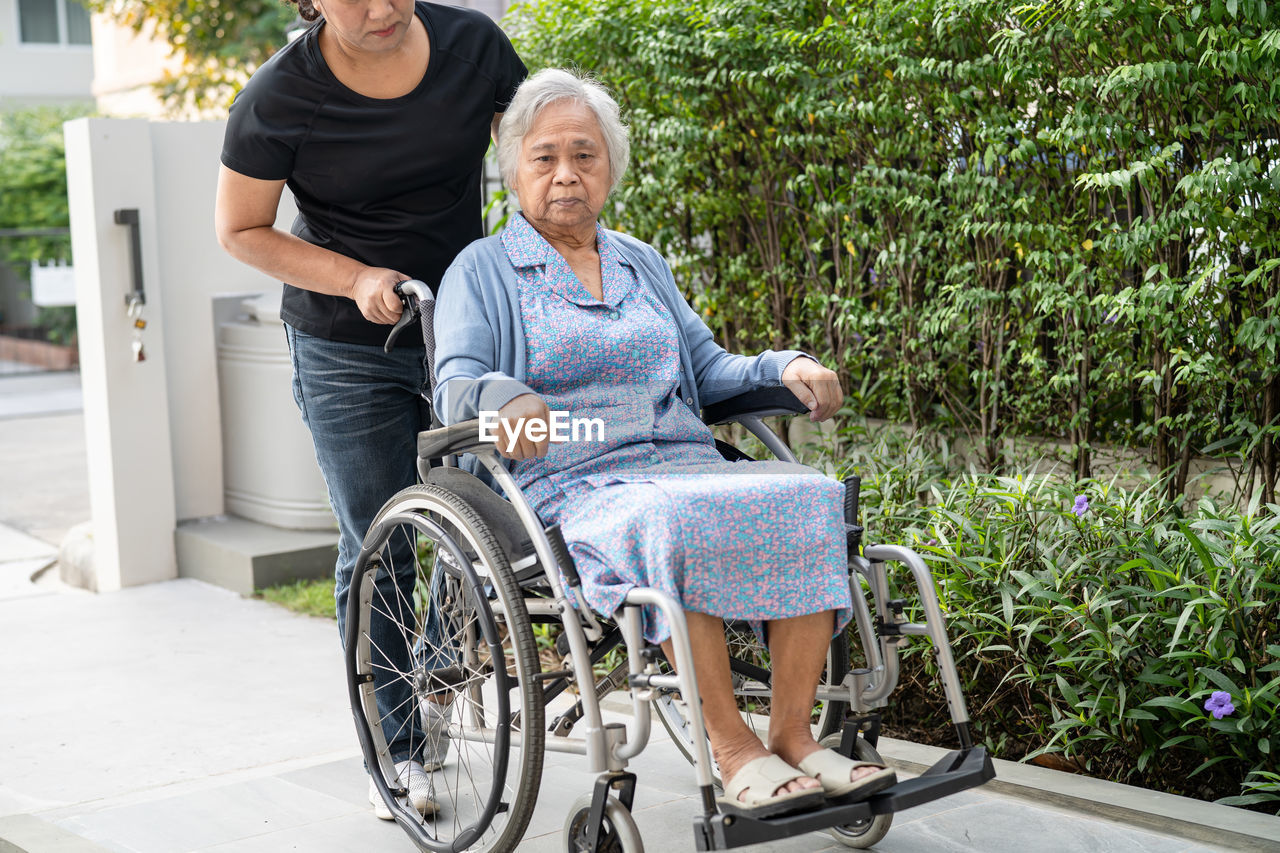 portrait of woman sitting on wheelchair in park