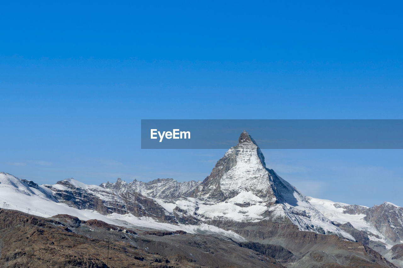 Scenic view of snowcapped mountains against clear blue sky