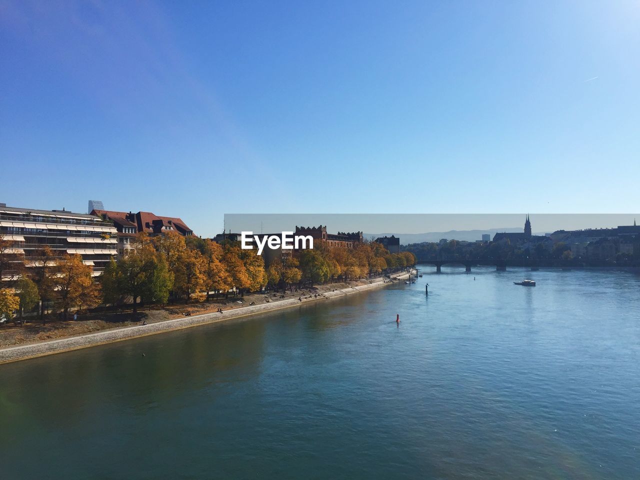 Scenic view of river by buildings against clear blue sky