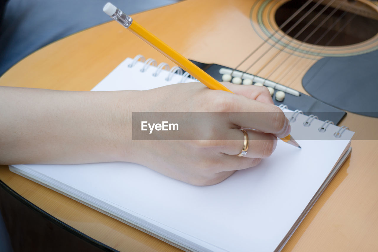 High angle view of men writing on diary while playing guitar