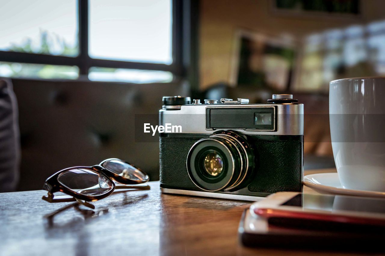 CLOSE-UP OF CAMERA ON TABLE WITH EYEGLASSES