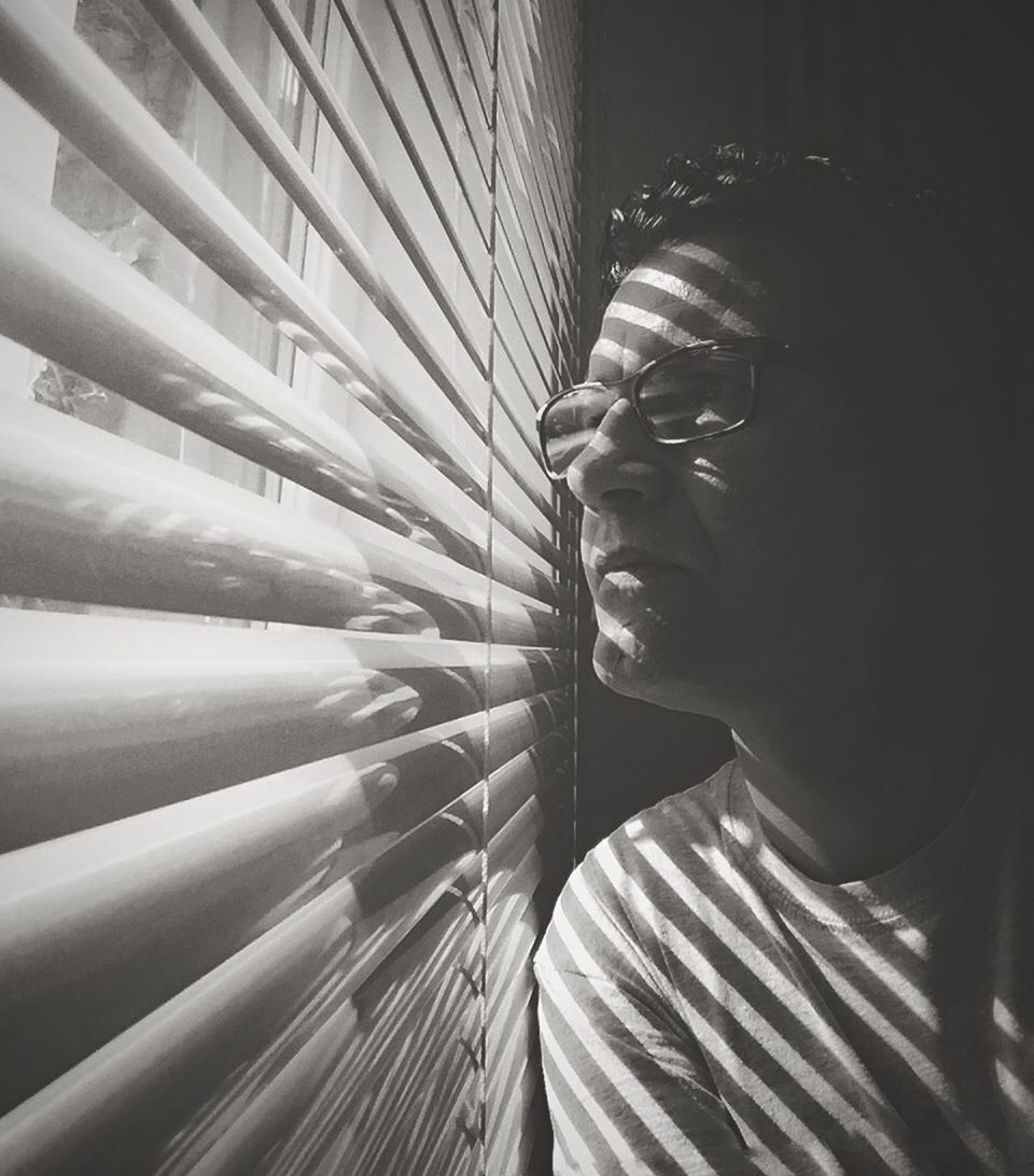 Man looking through window blinds