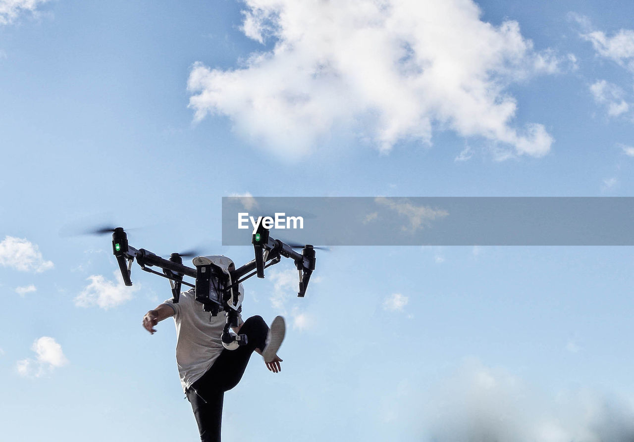 Low angle view of man with drone against sky