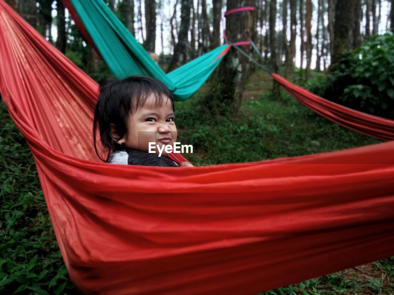 Portrait of happy child sitting on hammock at playground