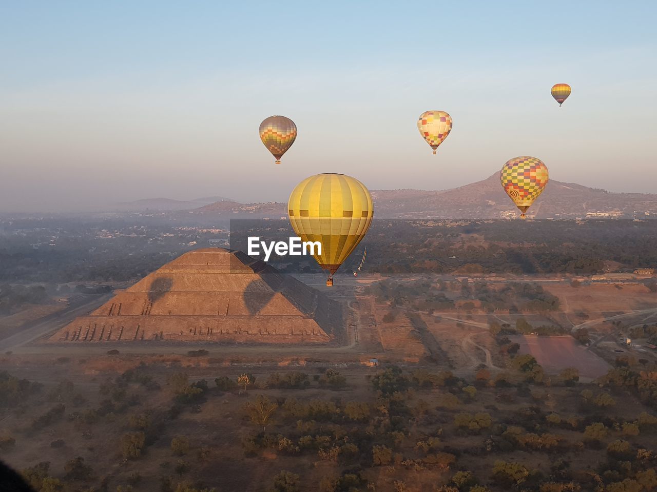 Hot air balloons flying over ancient pyramid