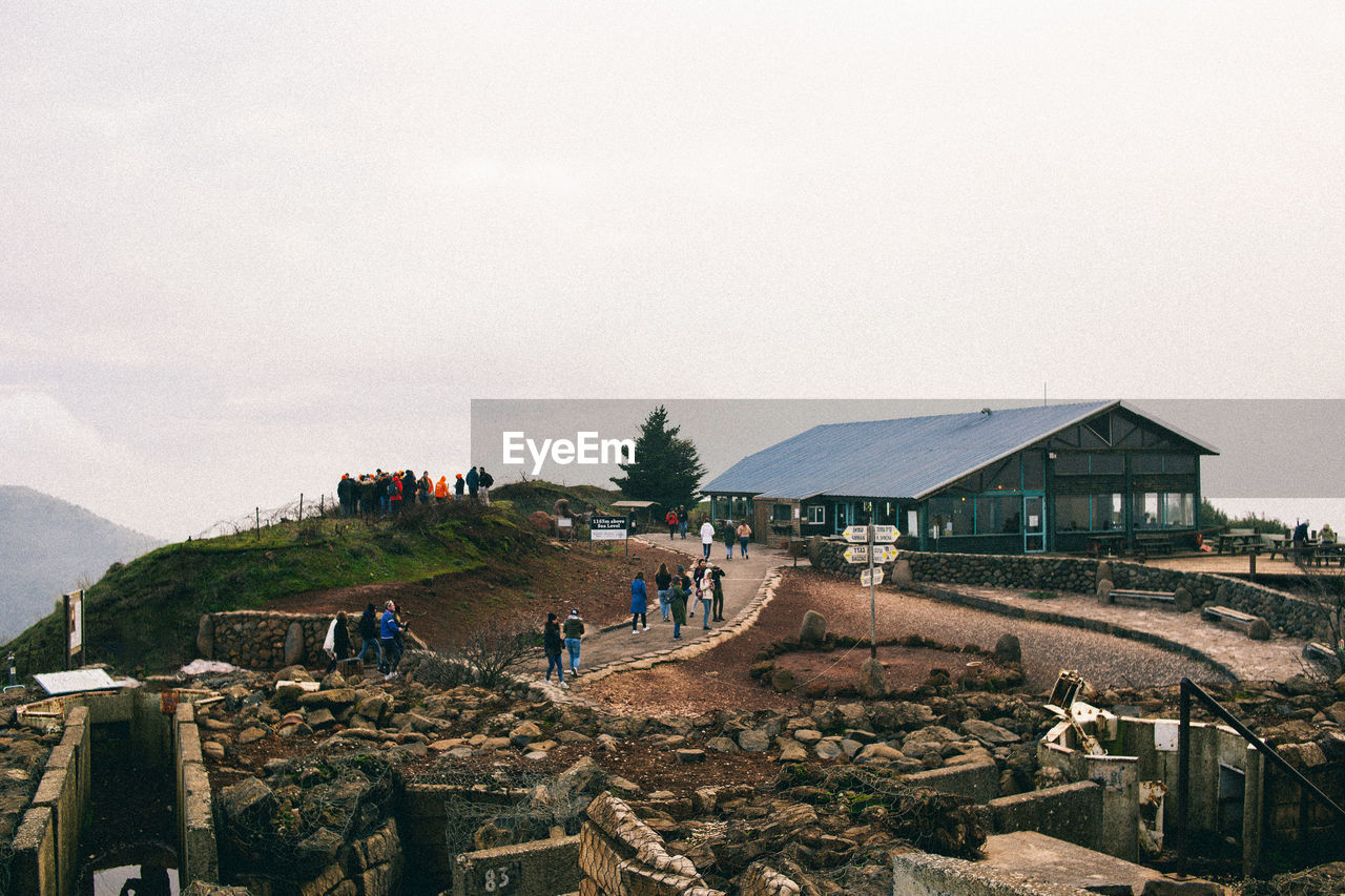 GROUP OF PEOPLE ON MOUNTAIN AGAINST BUILDINGS