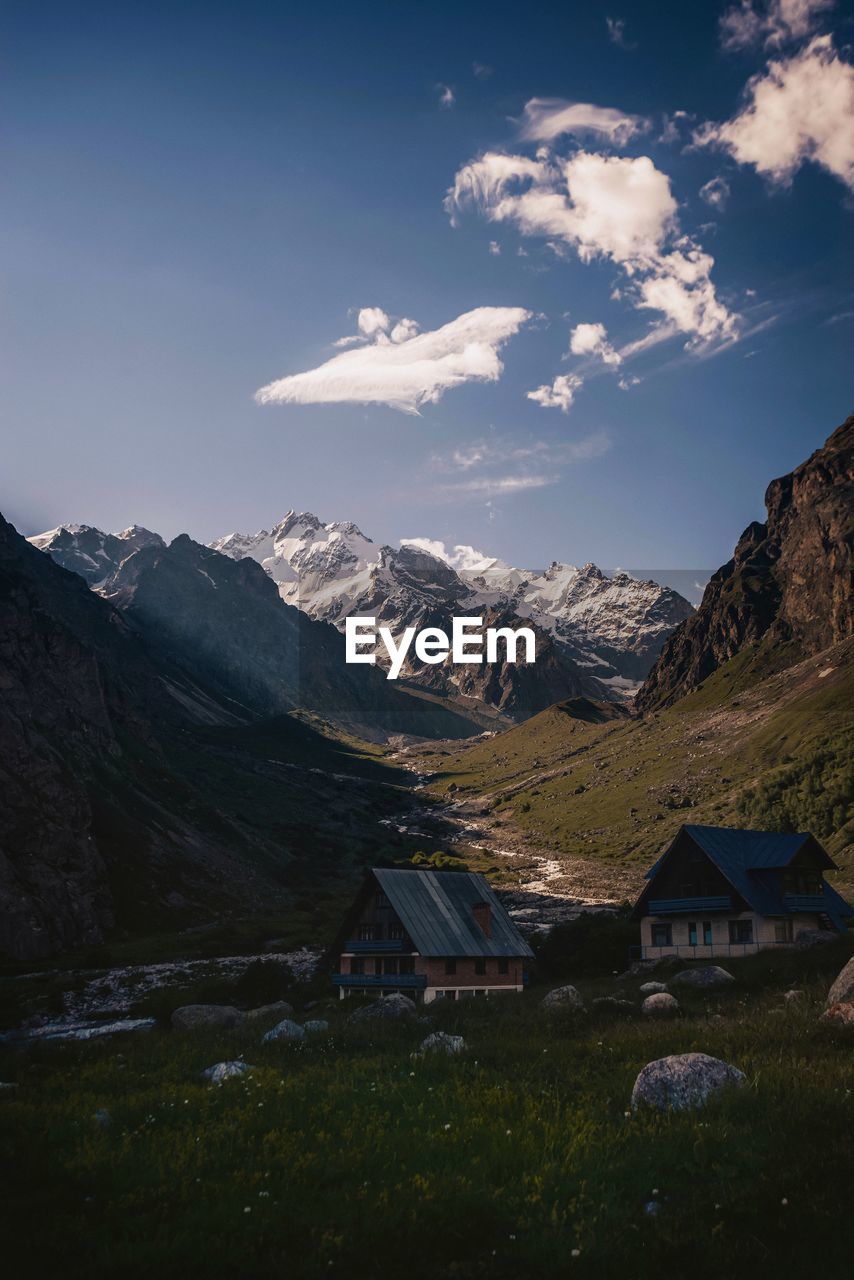 SCENIC VIEW OF MOUNTAINS AND HOUSES AGAINST SKY