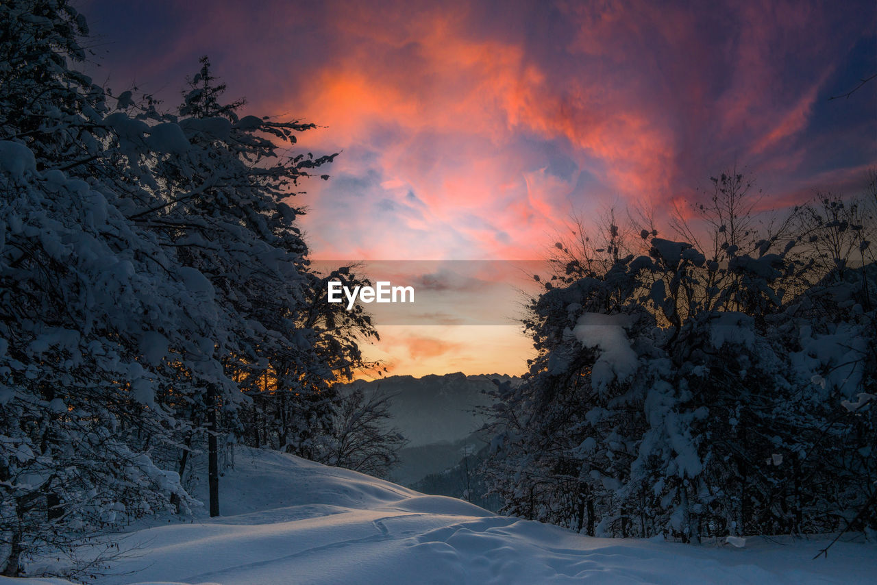 Scenic view of snow covered mountains against sky at sunset