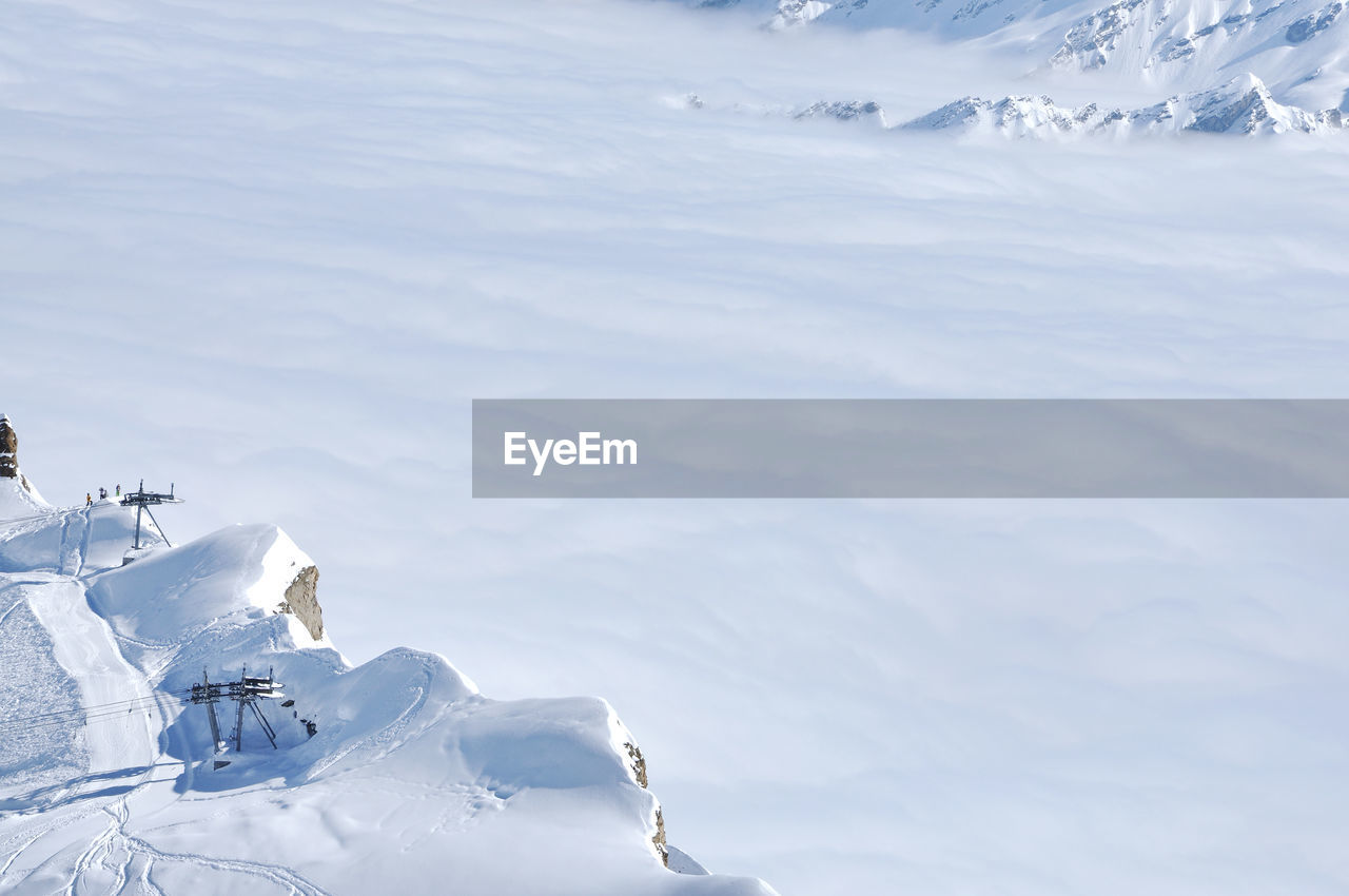 Fog above in the valley at winter in snow covered mountains