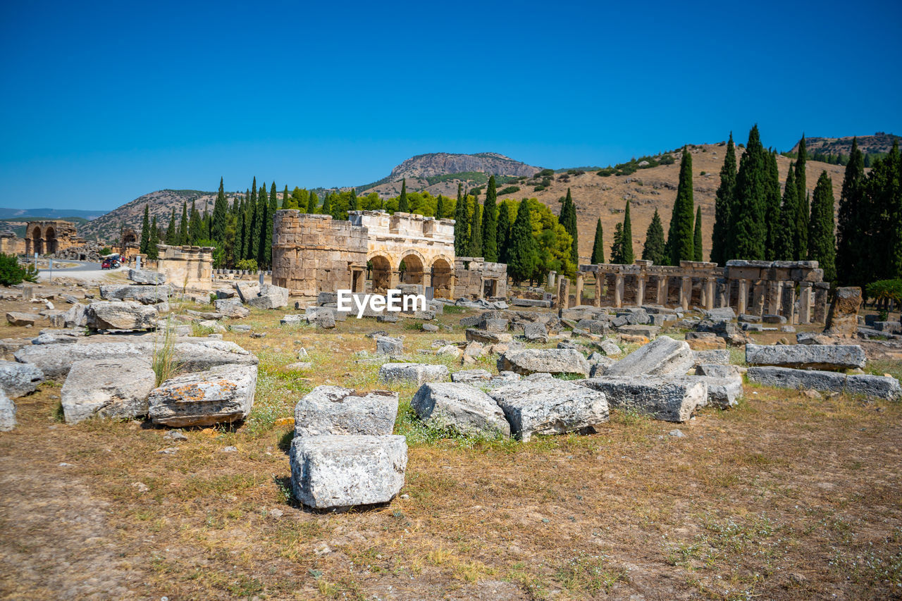 panoramic view of rocks on field against clear blue sky