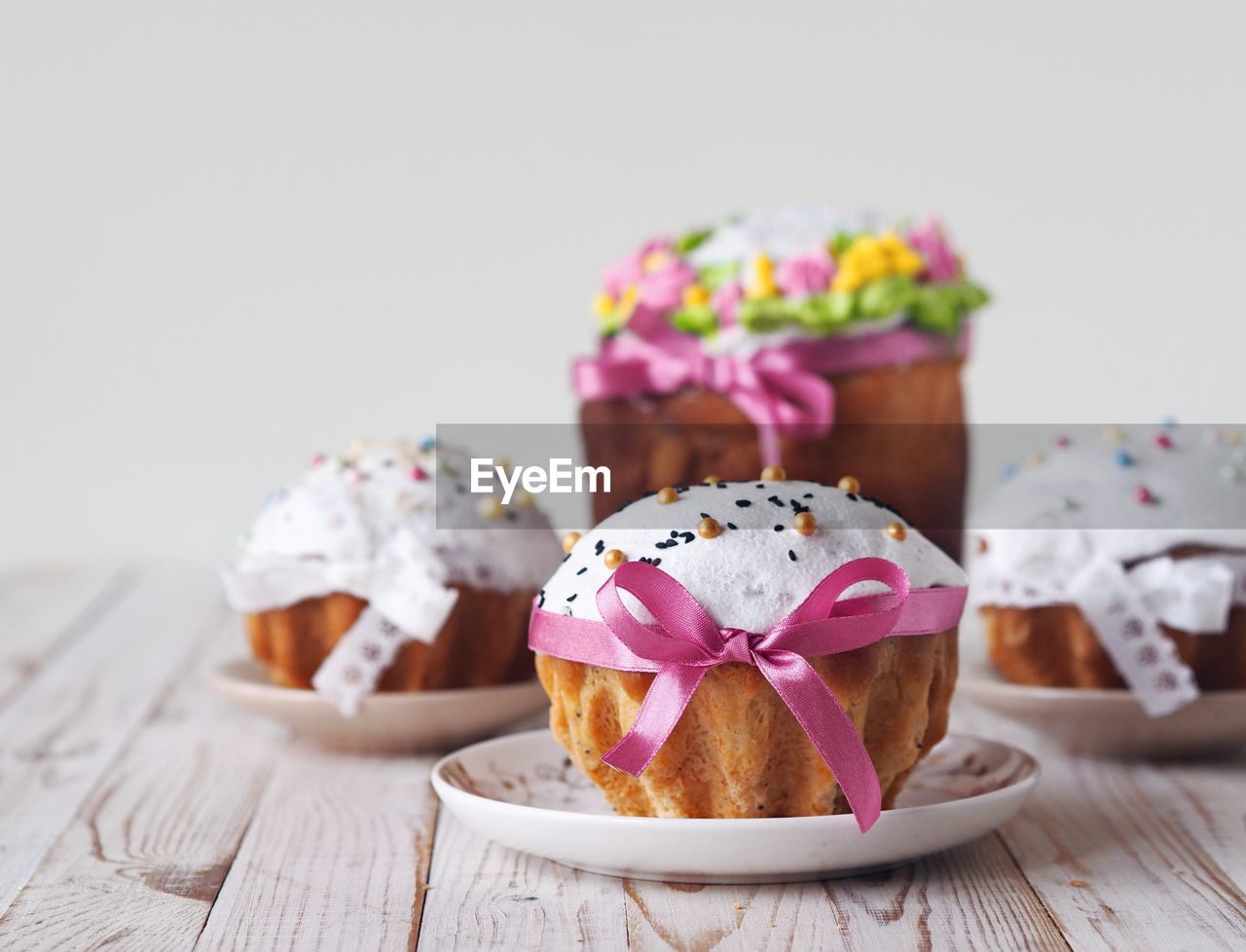 Easter pastries decorated with pastry sprinkles and ribbons on a white wooden background.