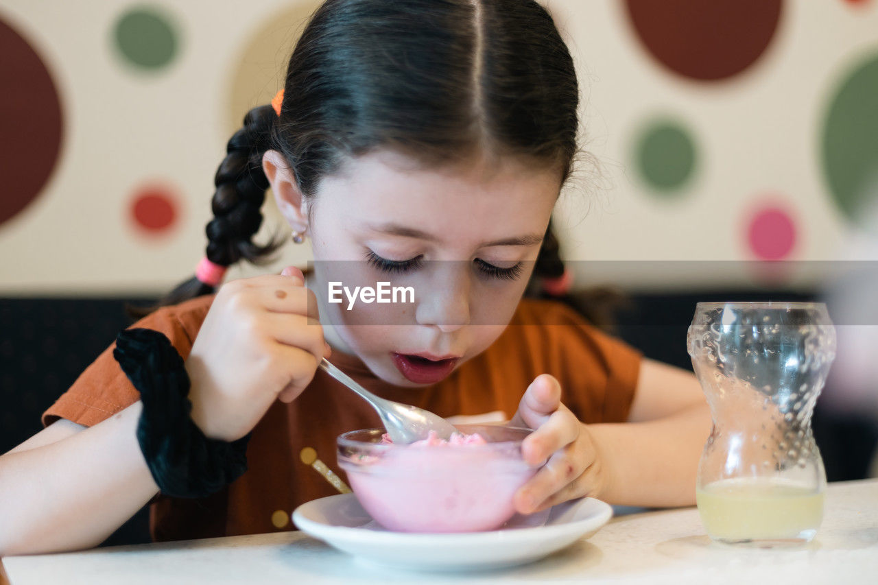 Portrait of a caucasian girl eating ice cream in a cafe.