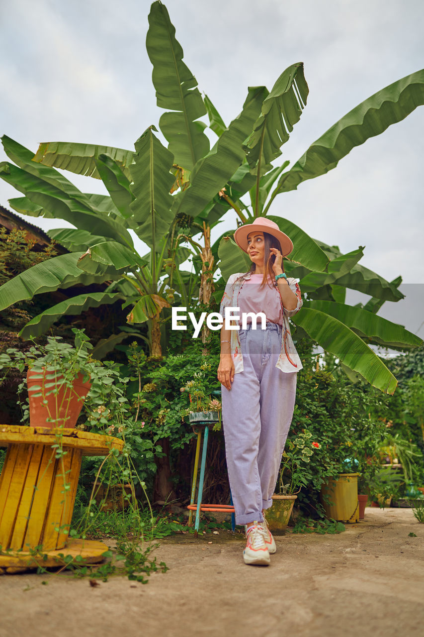 Portrait of young woman standing against plants