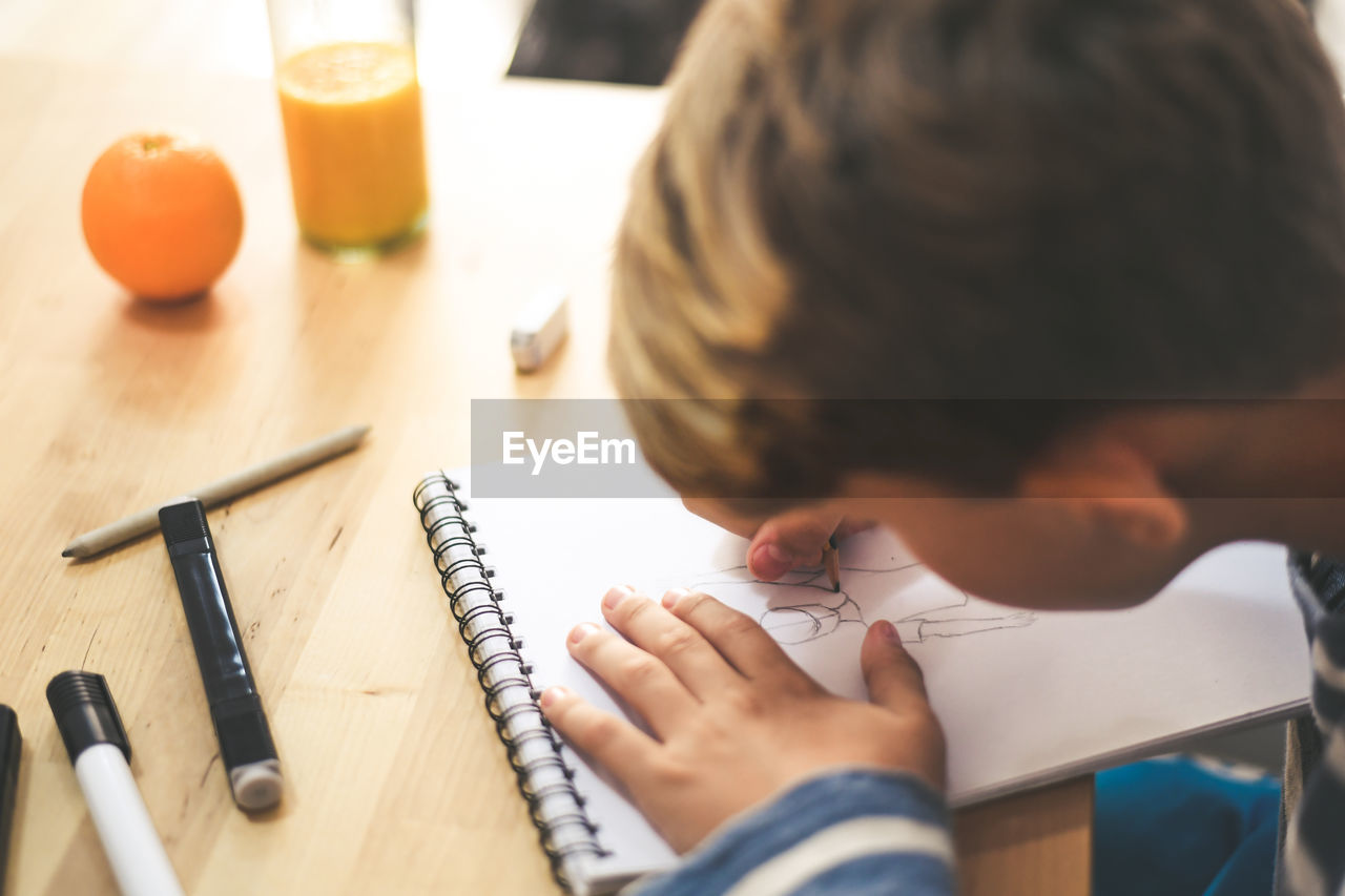 Boy making sketch on note pad at table