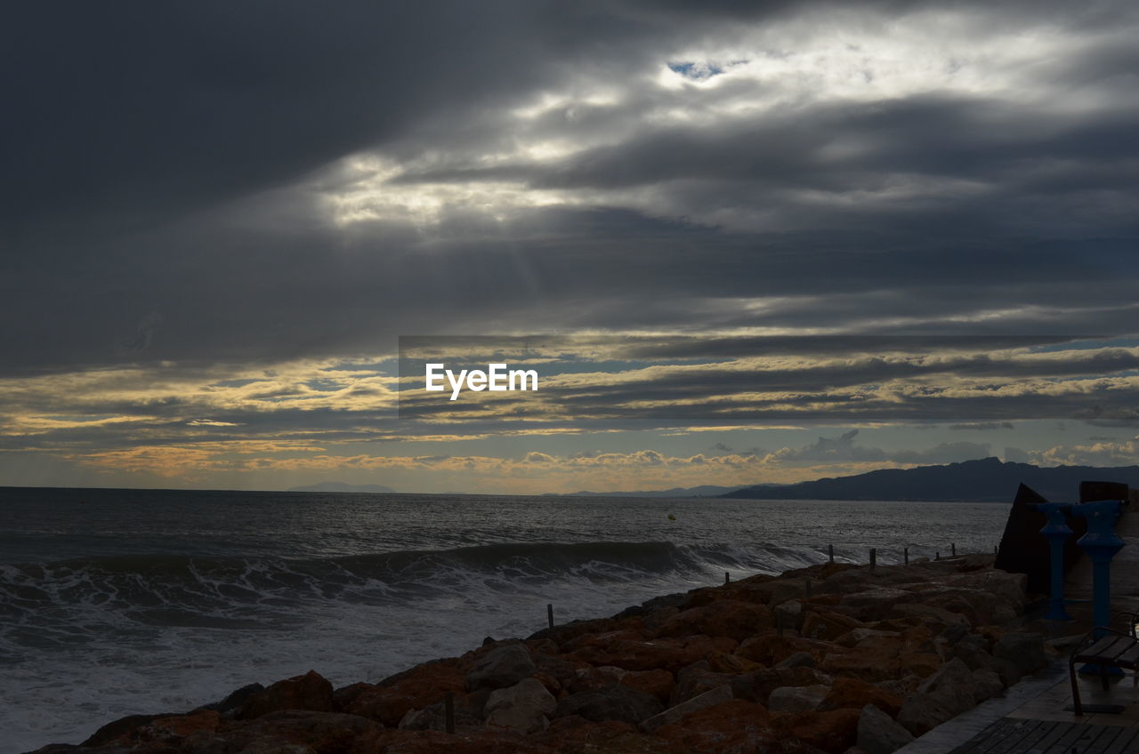 Scenic view of levante beach against cloudy sky at dusk