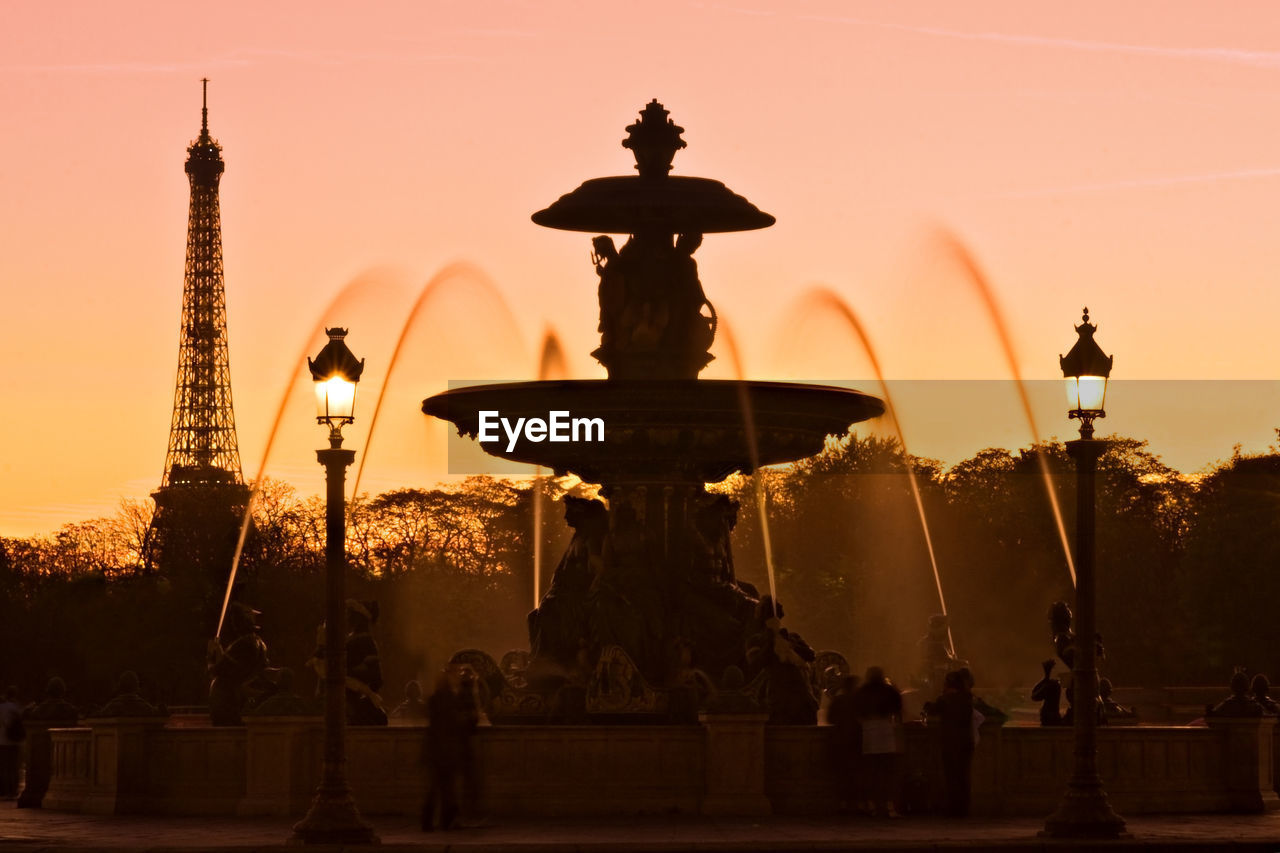 Fountain against eiffel tower during sunset