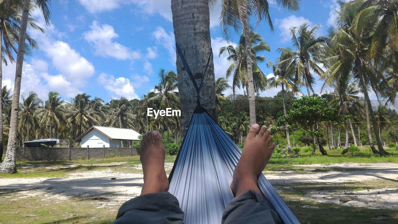 Low section of person lying on hammock at field