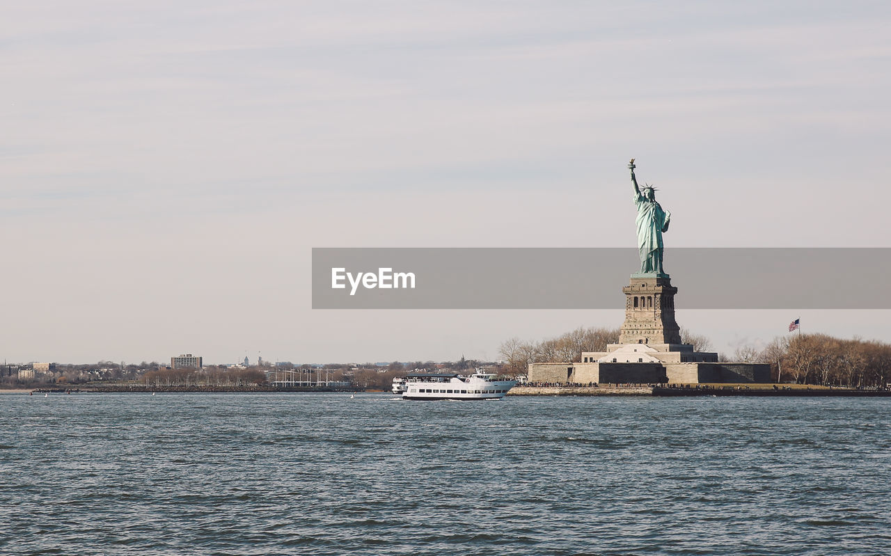 Statue of liberty by hudson river against sky