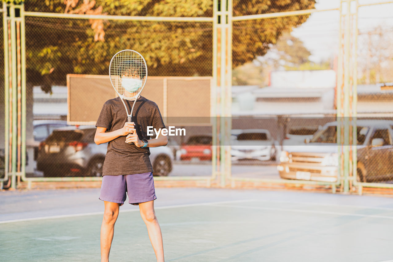 Boy holding tennis racket standing outdoors