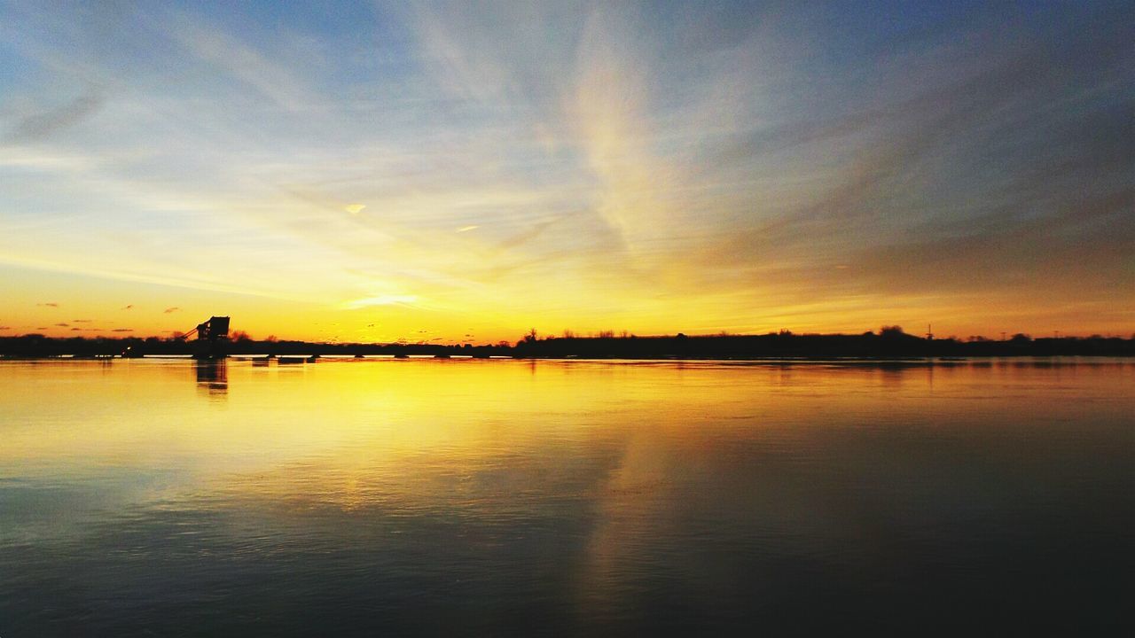 Scenic view of dramatic sky over lake during sunset