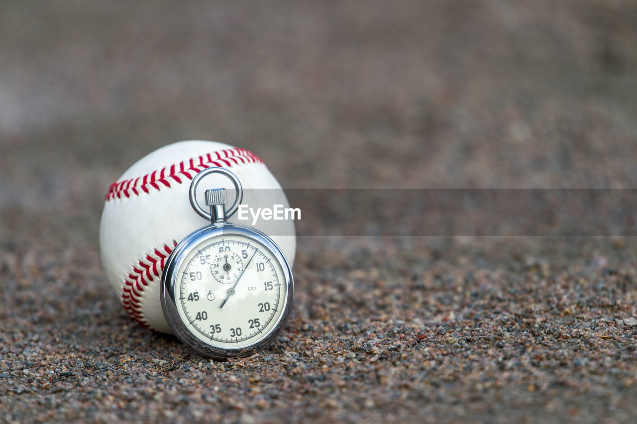 Close-up of ball and stopwatch on the ground