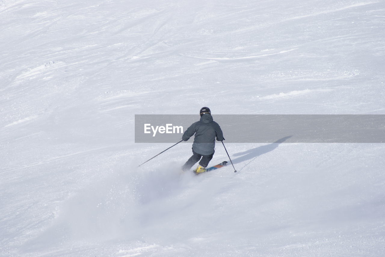 Rear view of man skiing on snow covered land