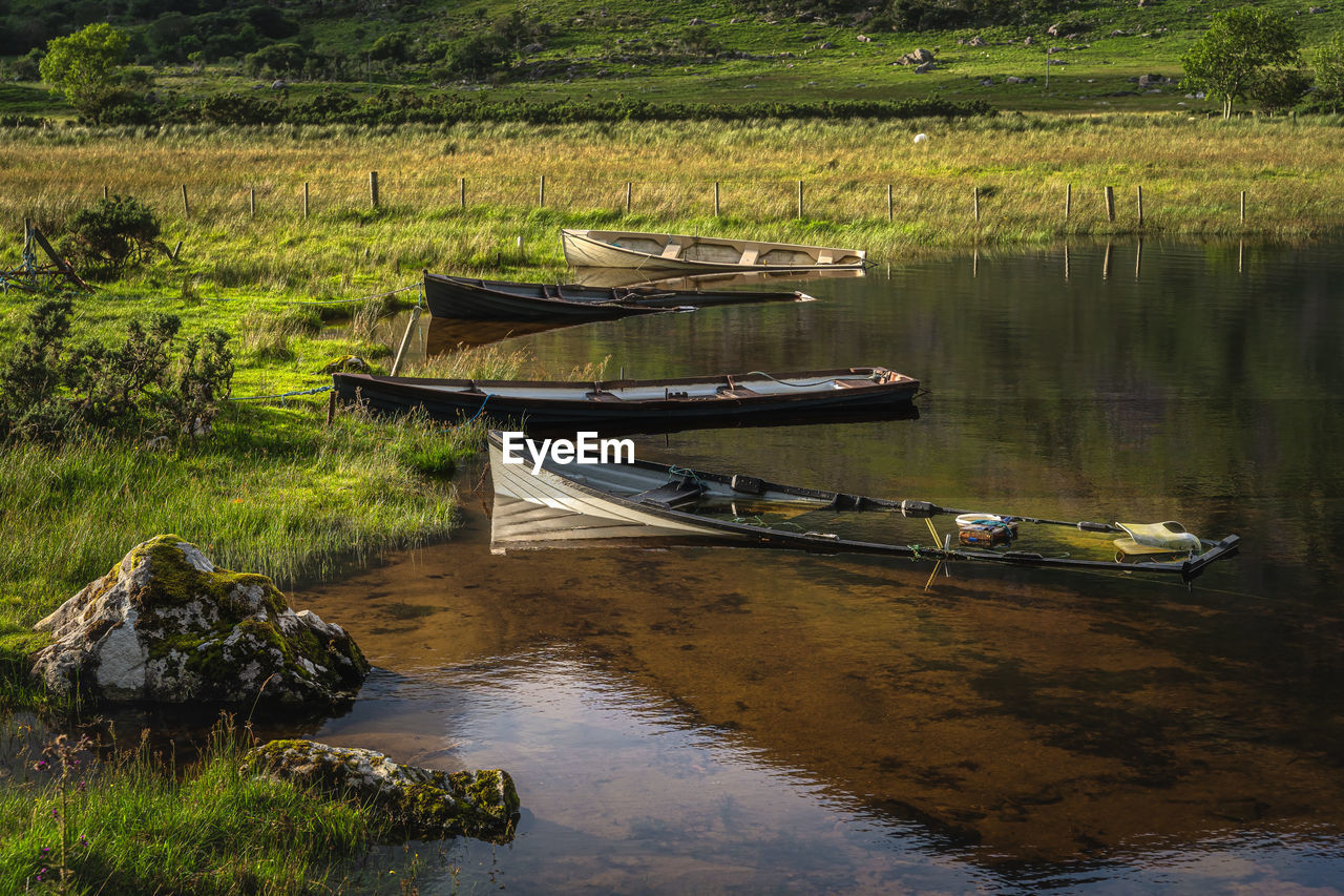 Sunken paddle boats in lough gummeenduff in beautiful black valley at sunset, ring of kerry, ireland