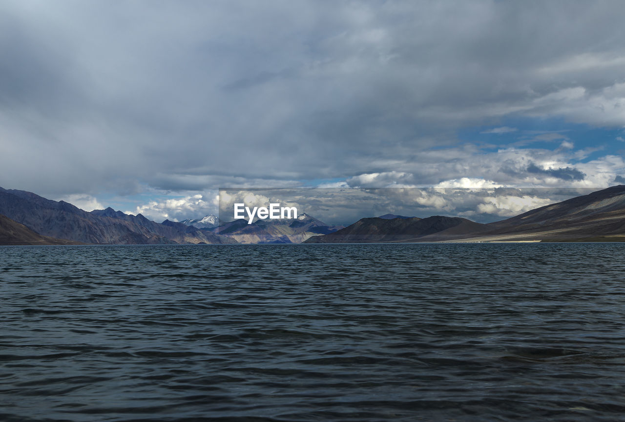 Scenic view of sea and snowcapped mountains against sky