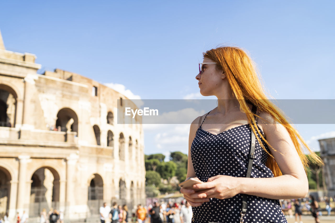 Young woman with smartphone admiring famous attraction