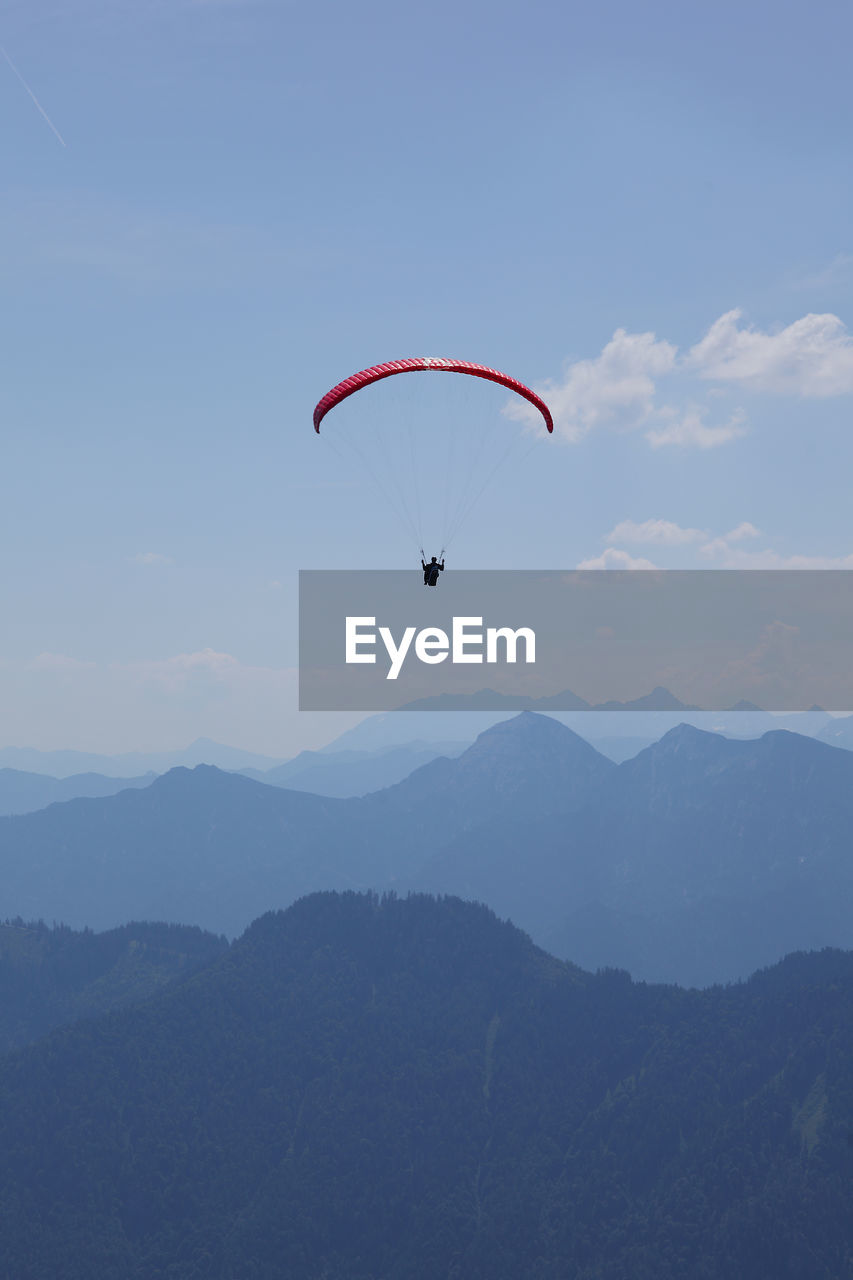 PERSON PARAGLIDING AGAINST MOUNTAIN RANGE