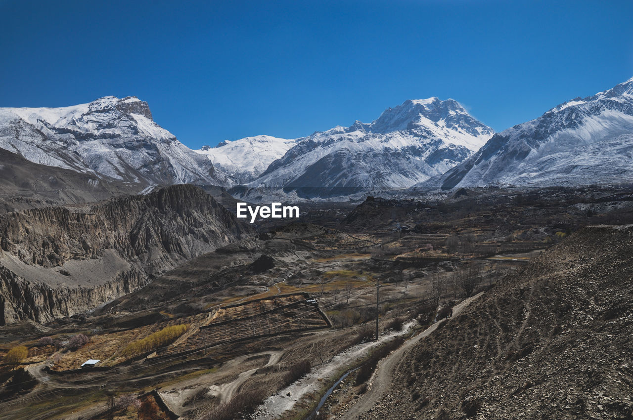 Scenic view of snowcapped mountains against blue sky