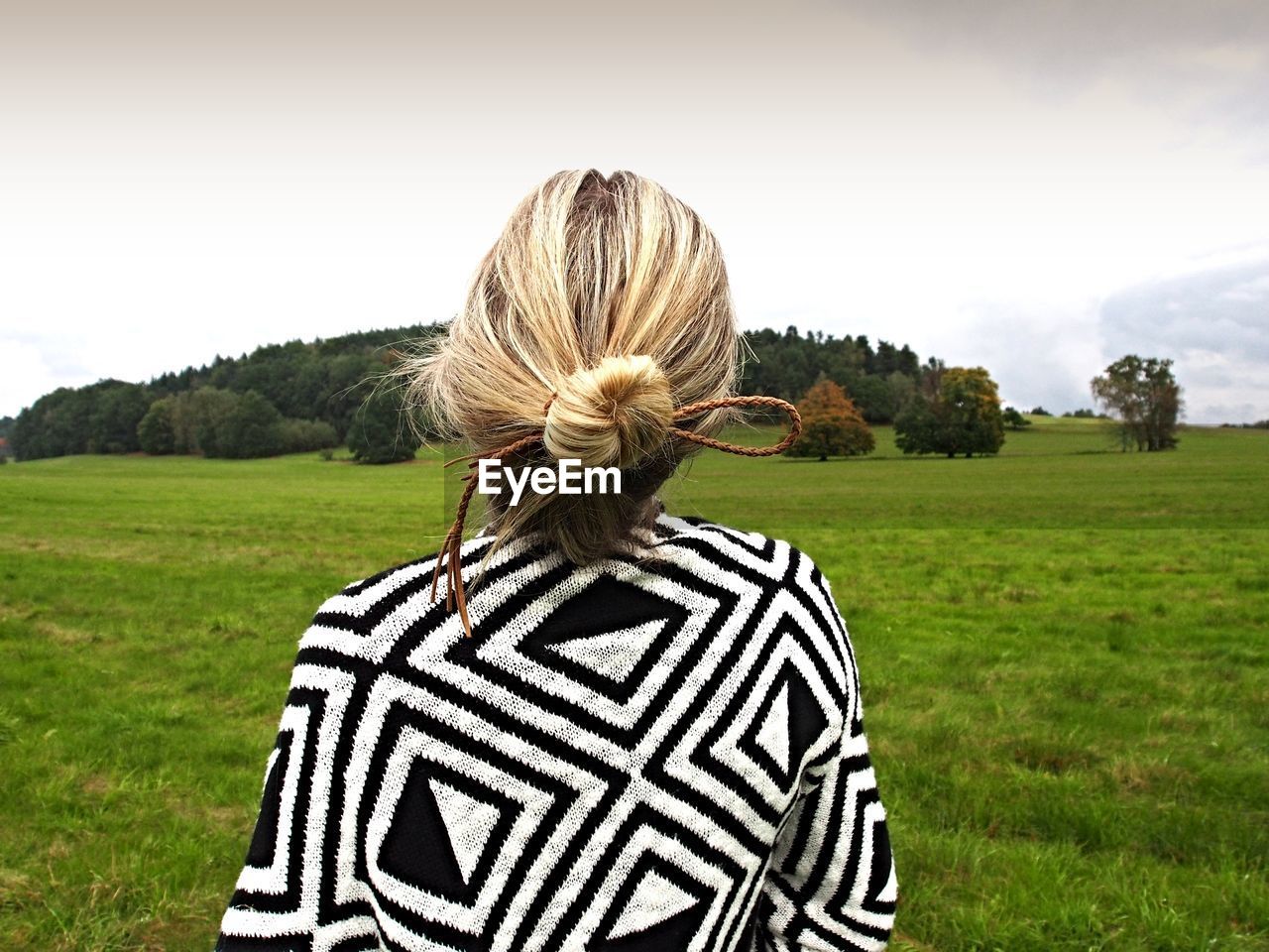 Rear view of woman on grassy field against sky