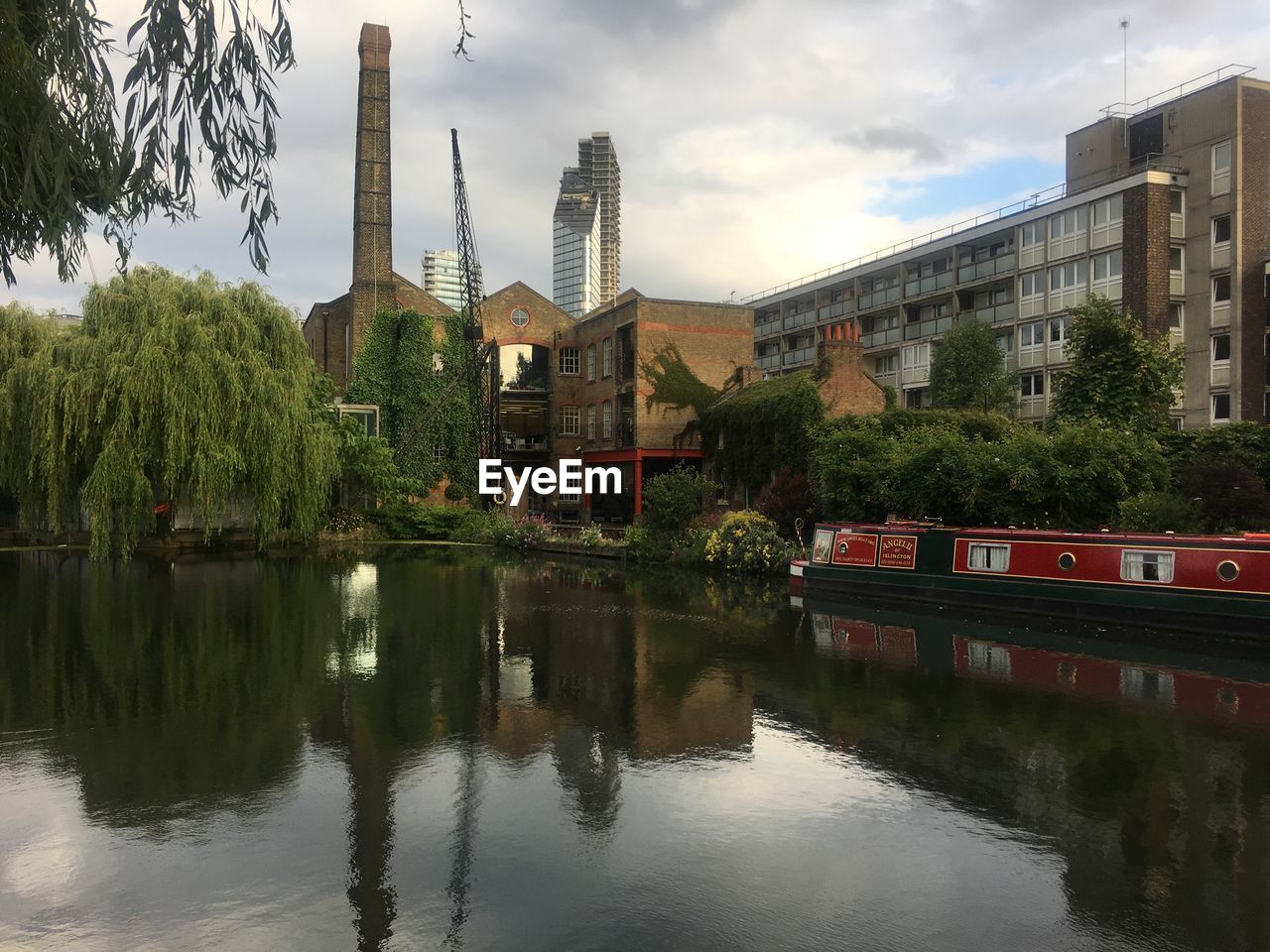 Reflection of trees and buildings in river against sky
