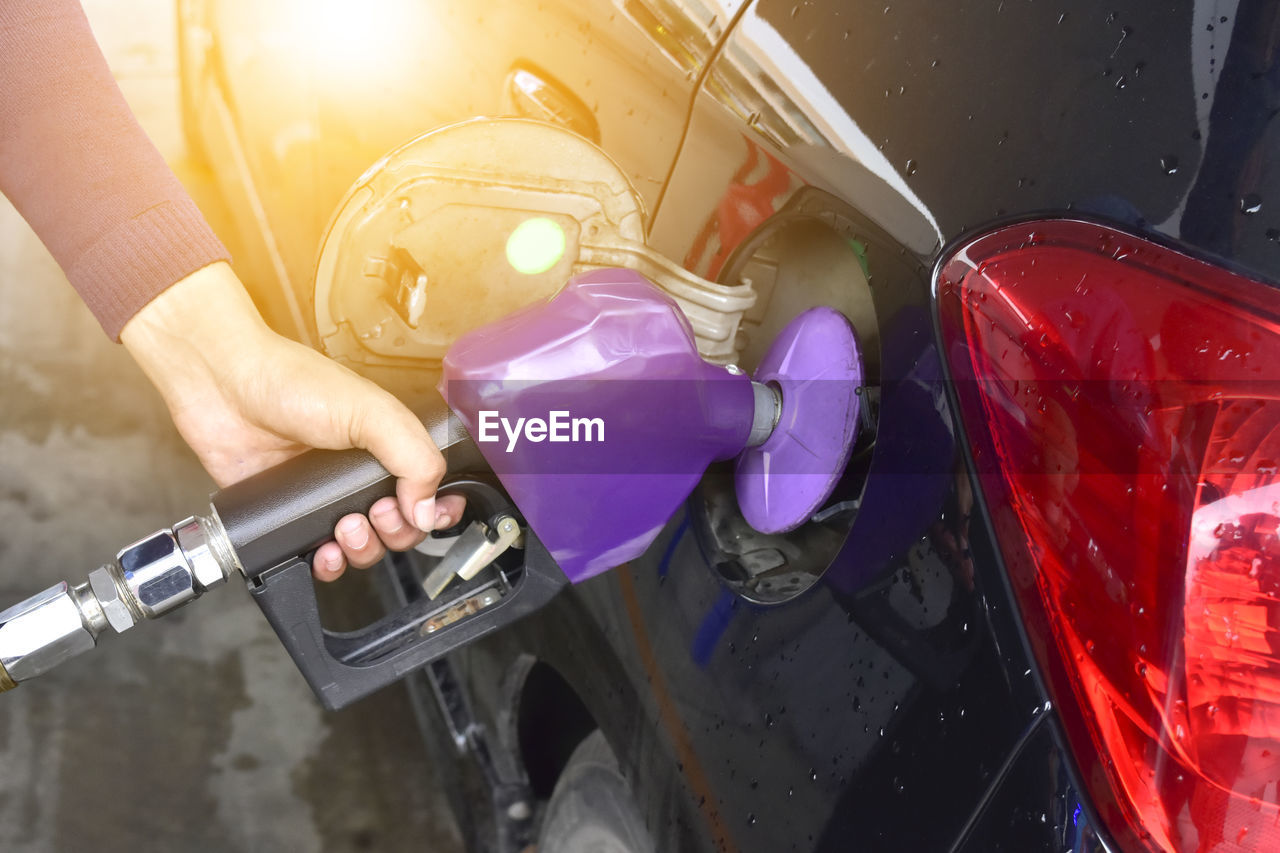 Cropped hand refueling car at gas station