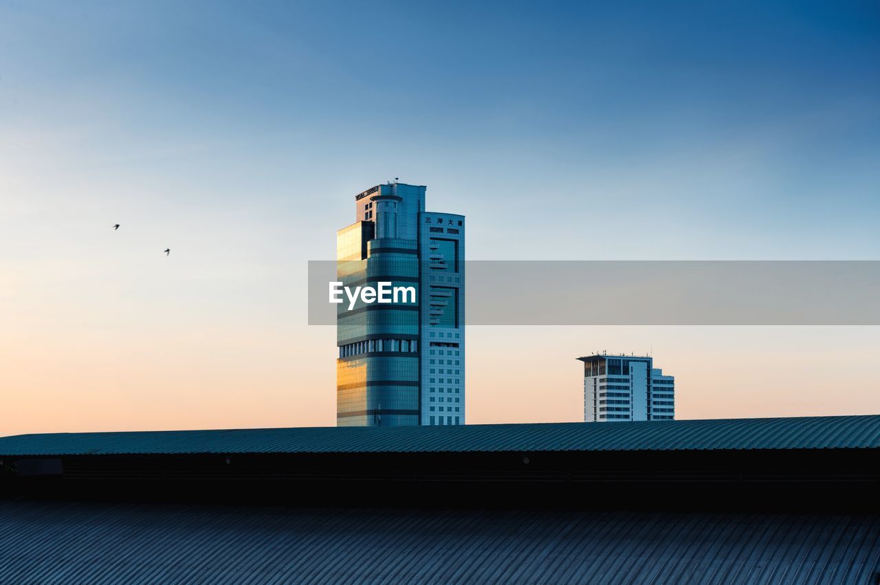 Low angle view of birds flying by building against sky