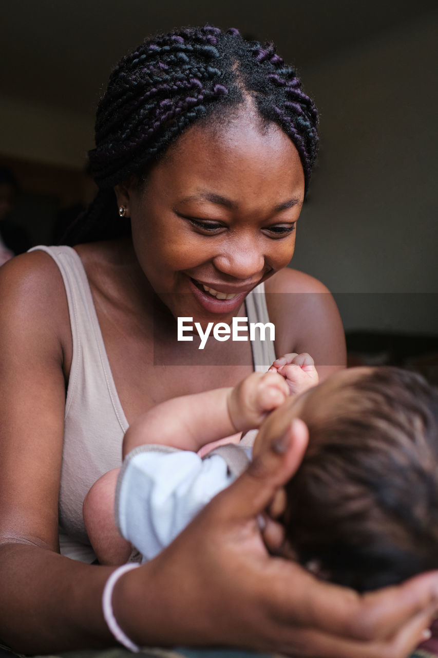 Loving african american mom cuddling and holding newborn baby while enjoying pleasant motherhood moments