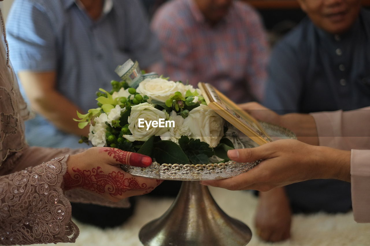 Cropped hands of wedding couple holding bouquet