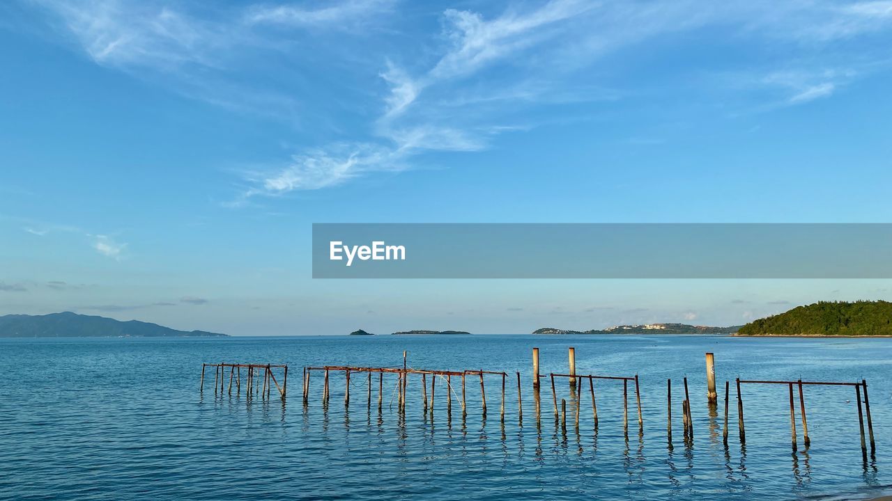 water, sky, shore, horizon, sea, ocean, scenics - nature, beauty in nature, nature, body of water, cloud, tranquility, tranquil scene, blue, vacation, beach, bay, coast, no people, land, pier, idyllic, day, wood, outdoors, travel destinations, travel, wave, non-urban scene, wooden post, horizon over water, mountain, holiday, architecture, reflection, seascape, sunlight, post, trip, summer