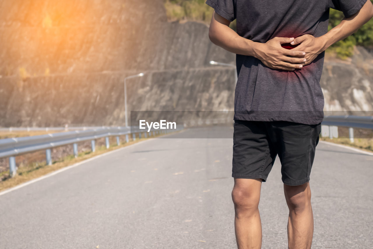 Low section of man standing on road