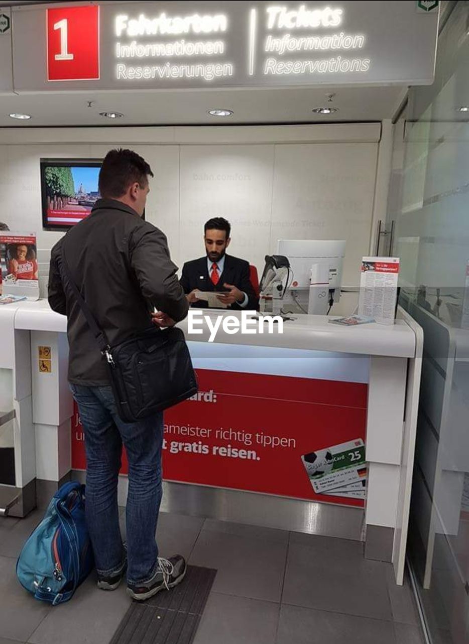 Rear view of man standing at ticket counter